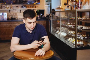 Genç yakışıklı adam bir kafede oturur.