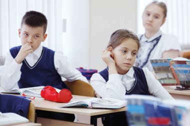 Şirin kız öğrenci sınıf masasında oturan.