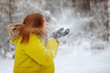 Genç, güzel, neşeli kızıl uzun saçlı kadın kışın dışarıda.