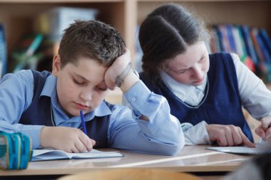 Sınıf içinde bir masada oturan bir genç liseli.