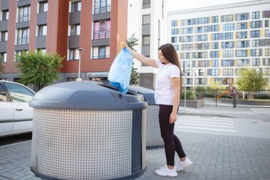 Kadın plastik poşeti çöplerle doldurmuş..