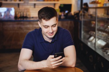 Genç yakışıklı adam bir kafede oturur.