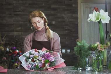 Bir önlük güzel orta yaşlı çiçekçi kadın bir buket toplar.