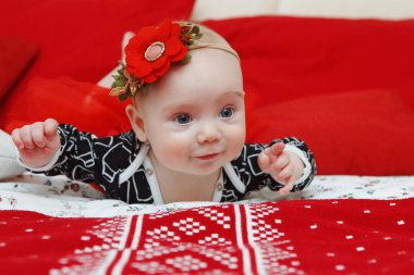 Baş elbisesini kırmızı bir arka plan üzerinde bir çiçek güzel beş aylık bebek kız. Bebeğim bak. Anne bakım. Çocuk Bakımı. Yakın çekim.