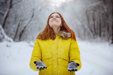 Genç, güzel, neşeli kızıl uzun saçlı kadın kışın dışarıda.