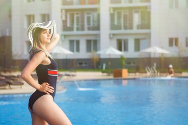 Uzun, güzel bacaklı, plaj şapkalı bir kadın...