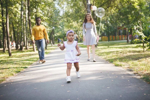 Chica de piel oscura, papá y mamá en el parque . — Foto de Stock