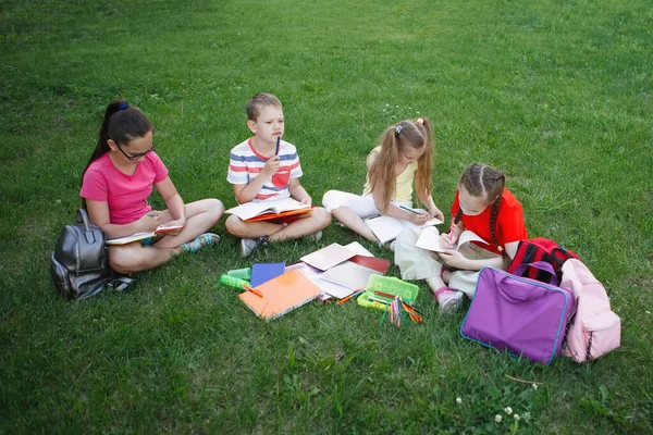 Quatro crianças sentadas na grama verde . — Fotografia de Stock