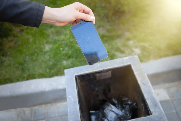 Girl's hand throws a smartphone into the trash. — Stock Photo, Image