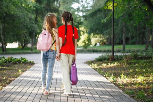 İki genç kız parkta kaldırımda yürüyor.. — Stok fotoğraf