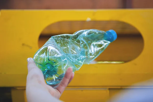 Old hand holding plastic bottle in to trash — Stock Photo, Image