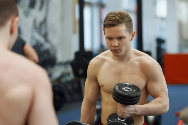 Młody, sportowiec facet podnoszenia hantle w siłowni. — Zdjęcie stockowe