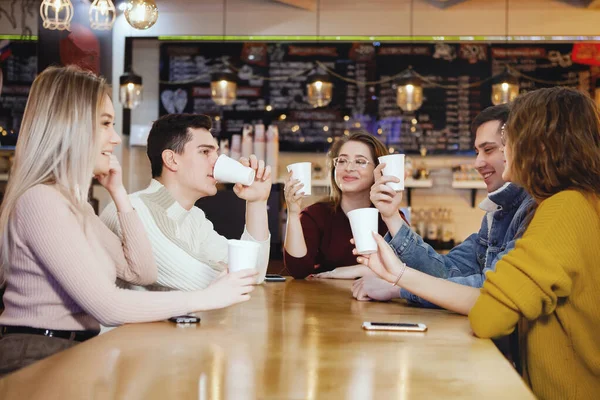 Cinco jovens estudantes bonitos sentados em um café . — Fotografia de Stock