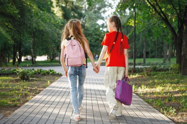 Duas meninas adolescentes caminham ao longo do pavimento no parque . — Fotografia de Stock