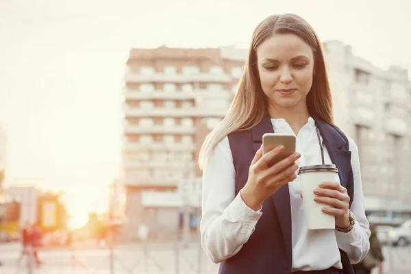 Mujer bonita joven con teléfono inteligente y taza de café de papel . — Foto de Stock