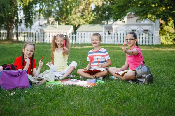 Quatro crianças sentadas na grama verde . — Fotografia de Stock