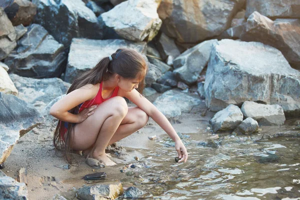 Giovane ragazza carina seduta vicino all'acqua . — Foto Stock