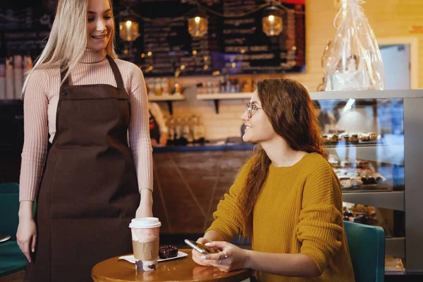 Jovem mulher bonita e garçonete no café . — Fotografia de Stock