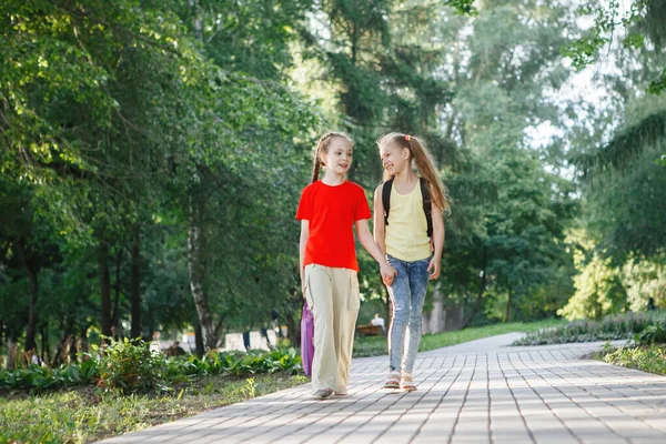 Dos adolescentes caminan por el pavimento en el parque . — Foto de Stock