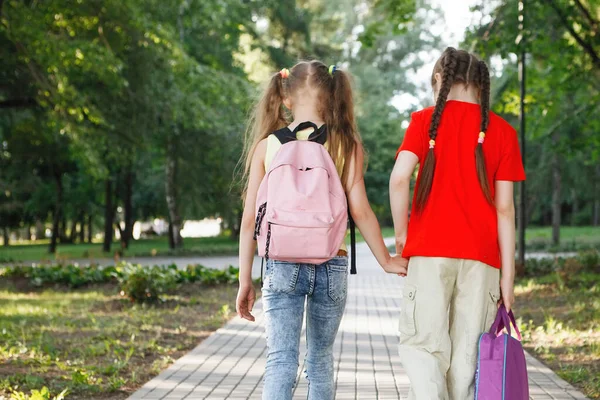 Duas meninas adolescentes caminham ao longo do pavimento no parque . — Fotografia de Stock