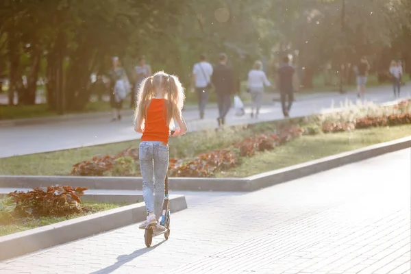 Tiener Kind rijden een scooter in een stadspark. — Stockfoto