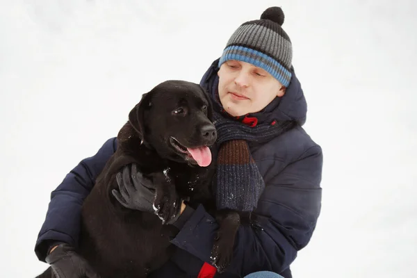 Homem divertido com seu labrador preto retriever na floresta de inverno . — Fotografia de Stock