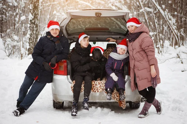 Οικογένεια σε καπέλα Χριστούγεννα στο πορτ-μπαγκάζ ενός αυτοκινήτου το χειμώνα για — Φωτογραφία Αρχείου