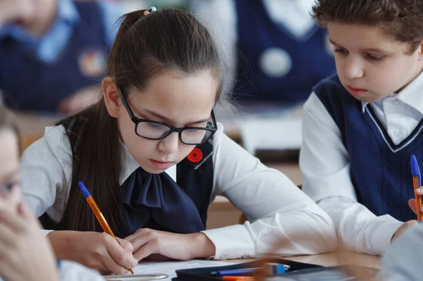 Schoolkinderen zitten tijdens de schooltijd aan hun bureau in de klas — Stockfoto