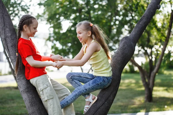 Twee tienermeisjes klimmen in bomen, lachen en lachen. — Stockfoto
