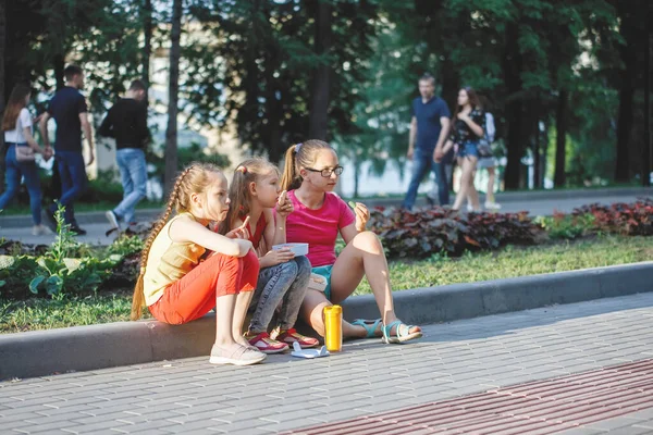 Adolescentes se sientan en la acera en el parque de la ciudad . — Foto de Stock