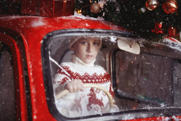 Junge fährt in rotem Weihnachtsauto. — Stockfoto