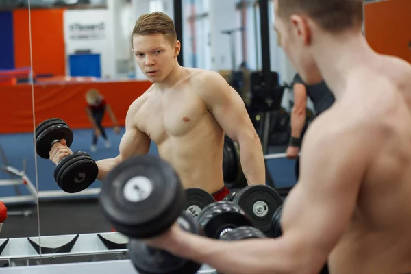 Joven atlético levantando pesas en el gimnasio . — Foto de Stock