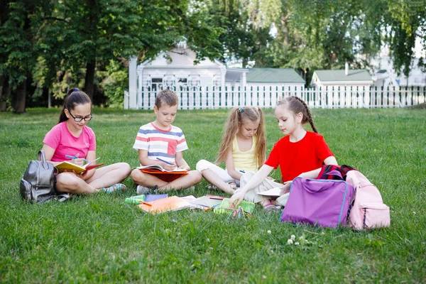 Four children sitting on the green grass. — Stock Photo, Image