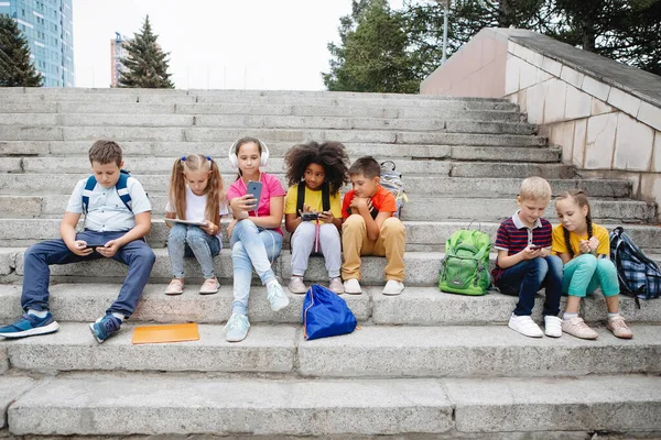 Groupe d'écoliers assis sur les marches de l'école — Photo