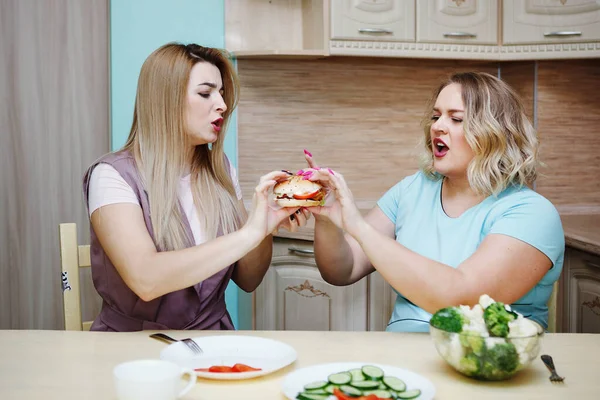 キッチンで 2 つのガール フレンド女性が楽しい時を過すそして食糧を食べる. — ストック写真
