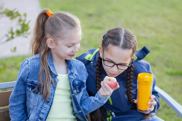 Tiener meisjes eten op een bankje in een stadspark. — Stockfoto