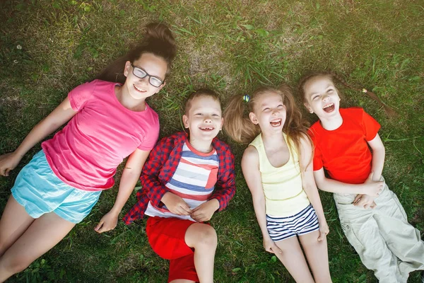 Kinderen liggend op het groene gras. — Stockfoto