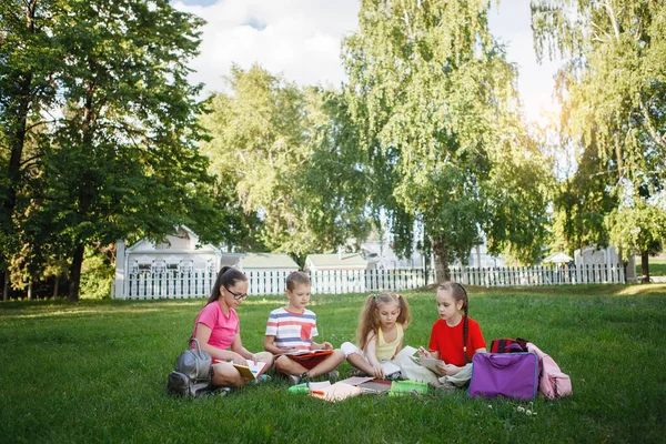 Cuatro niños sentados en la hierba verde . — Foto de Stock