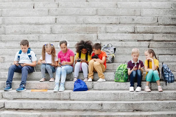 Grupo de escolares sentados en escalones escolares — Foto de Stock