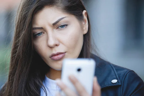 Mujer mira a un teléfono inteligente . — Foto de Stock