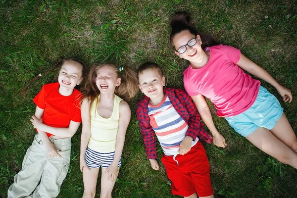 Kinderen liggend op het groene gras. — Stockfoto