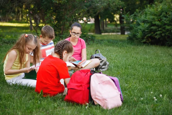Quatre enfants assis sur l'herbe verte . — Photo