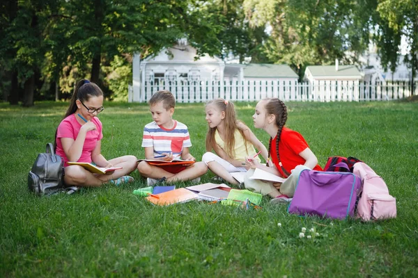 Quatre enfants assis sur l'herbe verte . — Photo