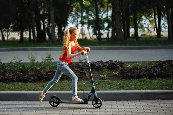 Adolescente niño montando una scooter en un parque de la ciudad . — Foto de Stock