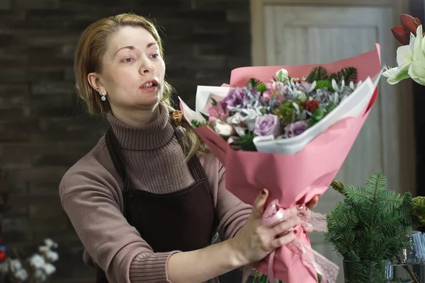 Fleuriste féminine dans un tablier marron montre à un acheteur un beau bouque — Photo