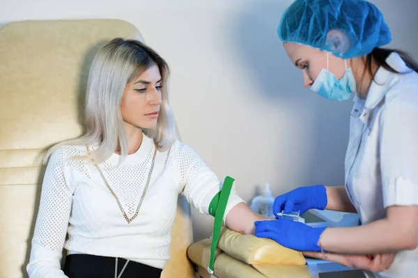 Une infirmière prélève un échantillon de sang dans une veine pour analyse chez un médecin. — Photo