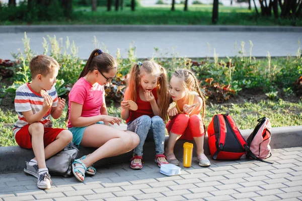 Tonåringar sitter på trottoaren i stadsparken. — Stockfoto