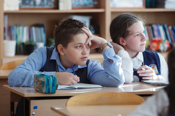 Un jeune écolier assis à un bureau dans une classe d'école . — Photo