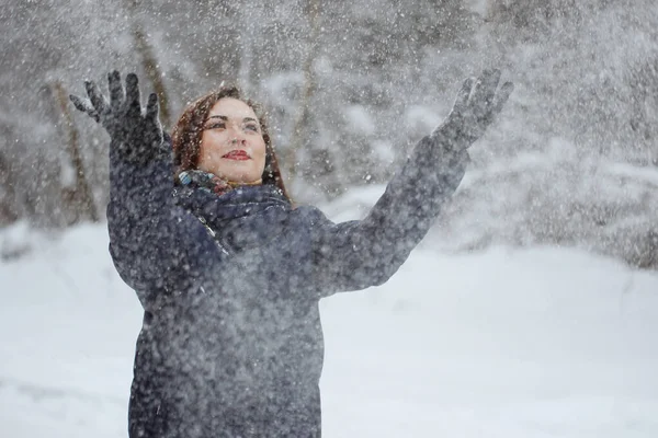 Mujer joven y bonita en una bufanda azul y chaqueta en un bosque cubierto de nieve —  Fotos de Stock