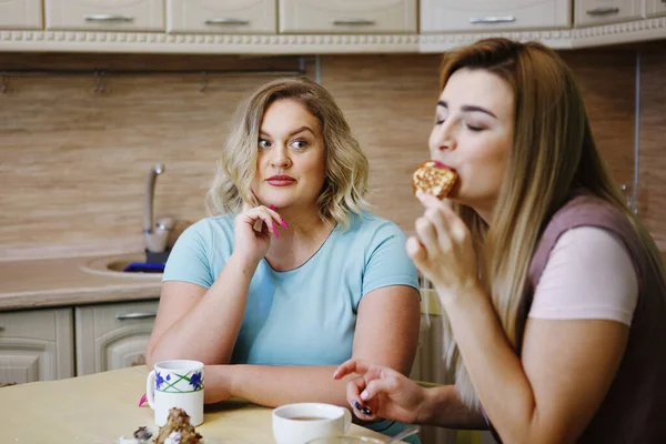 Dos novias mujeres en la cocina se están divirtiendo y comiendo comida . Fotos de stock libres de derechos